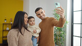 Fototapeta  - Couple and son make selfie by smartphone standing at home