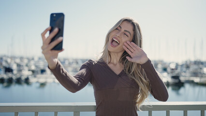 Poster - Young blonde woman smiling confident having video call at seaside