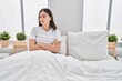 © Krakenimages.com - Young hispanic woman sitting on bed stressed with arms crossed gesture at bedroom