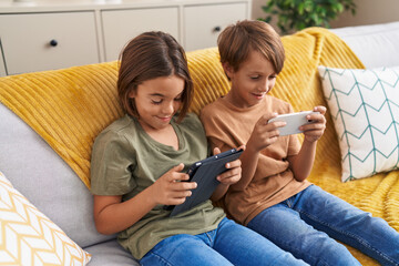 Poster - Adorable boys using smartphone and touchpad sitting on sofa at home