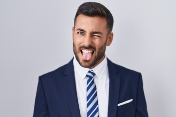 Canvas Print - Handsome hispanic man wearing suit and tie sticking tongue out happy with funny expression. emotion concept.