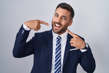 Canvas Print - Handsome hispanic man wearing suit and tie smiling cheerful showing and pointing with fingers teeth and mouth. dental health concept.