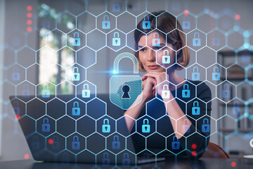 Wall Mural - Pensive attractive beautiful businesswoman in formal wear working on laptop at office workplace in background. Concept of data protection information technology. lock icon hologram.