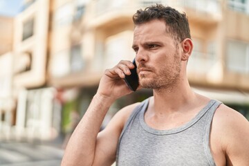 Wall Mural - Young hispanic man talking on the smartphone with serious expression at street