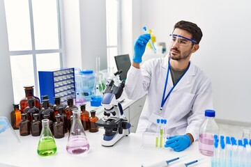 Sticker - Young hispanic man wearing scientist uniform holding test tube at laboratory