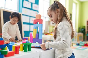 Wall Mural - Adorable boy and girl playing with construction blocks and vocabulary puzzle at kindergarten