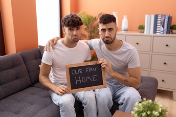 Poster - Homosexual gay couple holding blackboard with first home text depressed and worry for distress, crying angry and afraid. sad expression.