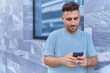 © Krakenimages.com - Young hispanic man using smartphone with serious expression at street