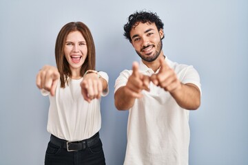 Canvas Print - Young couple wearing casual clothes standing together pointing to you and the camera with fingers, smiling positive and cheerful