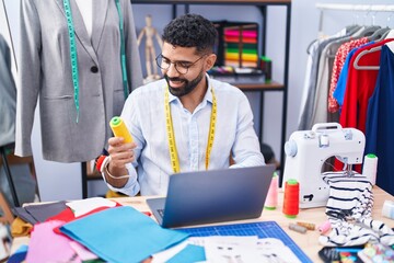 Sticker - Young arab man tailor using laptop holding thread at tailor shop