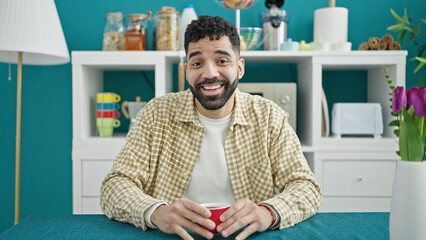 Sticker - Young hispanic man drinking coffee sitting on table at dinning room