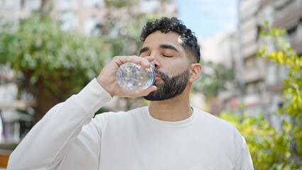 Sticker - Young hispanic man drinking water at park