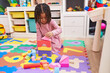 © Krakenimages.com - African american girl playing with wooden construction blocks sitting on floor at kindergarten