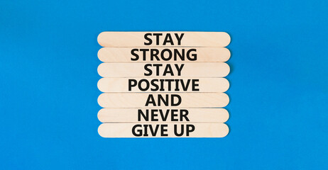 Wall Mural - Never give up symbol. Concept words Stay strong stay positive never give up on wooden stick. Beautiful blue table blue background. Copy space. Motivational business never give up concept.