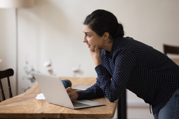 Canvas Print - Pensive Indian student or employee ponders over task, search solution, leaned at desk with laptop staring aside deep in thoughts, consider, prepare report or research, looks thoughtful, feels puzzled