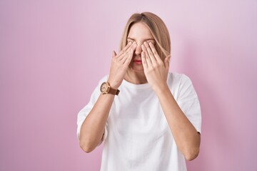 Poster - Young caucasian woman standing over pink background rubbing eyes for fatigue and headache, sleepy and tired expression. vision problem