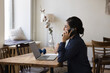 © fizkes - Indian businesslady talks on smartphone sit at desk with laptop, lead formal conversation, ask or provide information, communicates to customers support services use modern tech and mobile connection