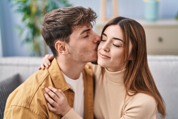 Poster - Mand and woman couple kissing and hugging each other sitting on sofa at home