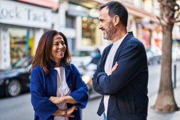 Poster - Middle age man and woman couple standing with arms crossed gesture at street