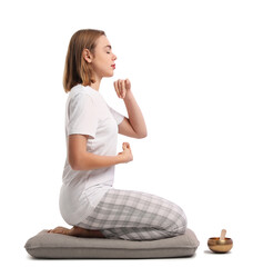 Wall Mural - Young woman meditating with Tibetan singing bowl on light background