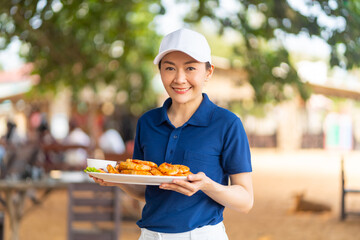 Wall Mural - Portrait of Asian woman waiter serving food and drink to customer on the table at tropical beach cafe and restaurant on summer holiday vacation. Food and drink business service occupation concept.