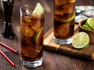 Rum and cola cocktail with lime slice in tall glasses