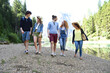 © fabrus - Group of friends of different nationalities on vacation in the middle of nature, walks on the river of an alpine lake and celebrate spring or summer