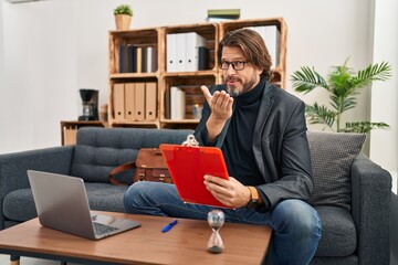 Canvas Print - Handsome middle age man working at consultation office looking at the camera blowing a kiss with hand on air being lovely and sexy. love expression.