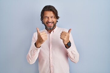 Poster - Handsome middle age man wearing elegant shirt background success sign doing positive gesture with hand, thumbs up smiling and happy. cheerful expression and winner gesture.