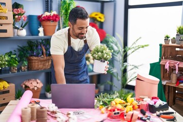 Sticker - Young hispanic man florist using laptop holding plant pot at florist