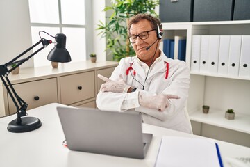 Sticker - Senior doctor man working on online appointment pointing to both sides with fingers, different direction disagree