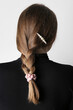 Woman with pigtail and silk scrunchy on light background, back view
