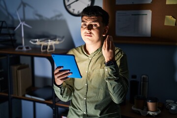 Canvas Print - Non binary person using touchpad device at night doing italian gesture with hand and fingers confident expression