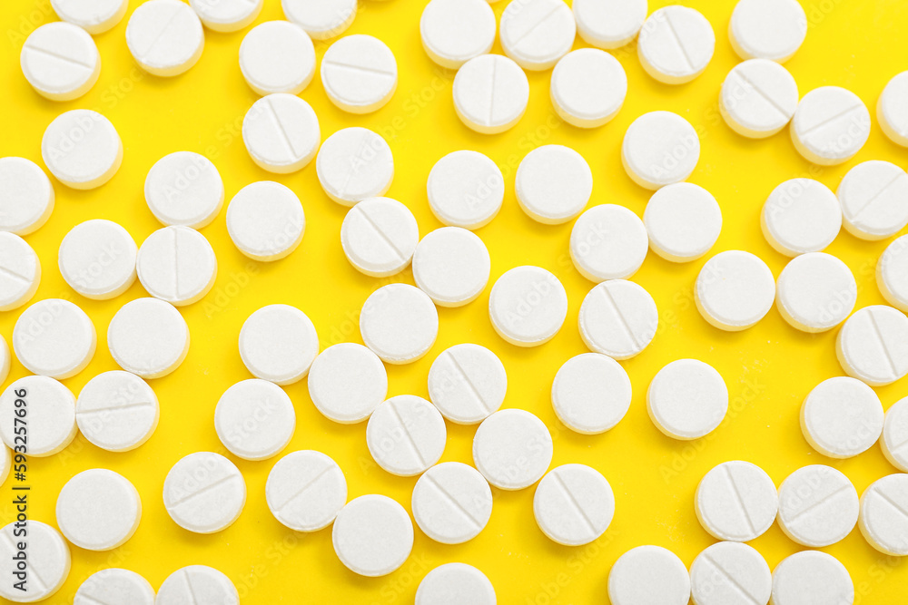White pills on yellow background
