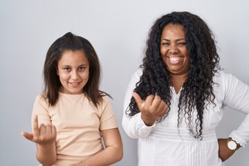 Sticker - Mother and young daughter standing over white background beckoning come here gesture with hand inviting welcoming happy and smiling