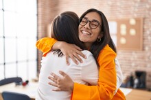 Two women business workers hugging each other at office