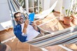 © Krakenimages.com - Middle age man using touchpad lying on hammock at terrace home