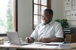 © Natee Meepian - African American man calculating using machine managing household finances at home, focused biracial male make calculations on calculator account taxes or expenses
