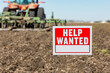 © JJ Gouin - Help wanted sign in farm field during spring planting season. Farm labor shortage, agriculture job market and employment concept.