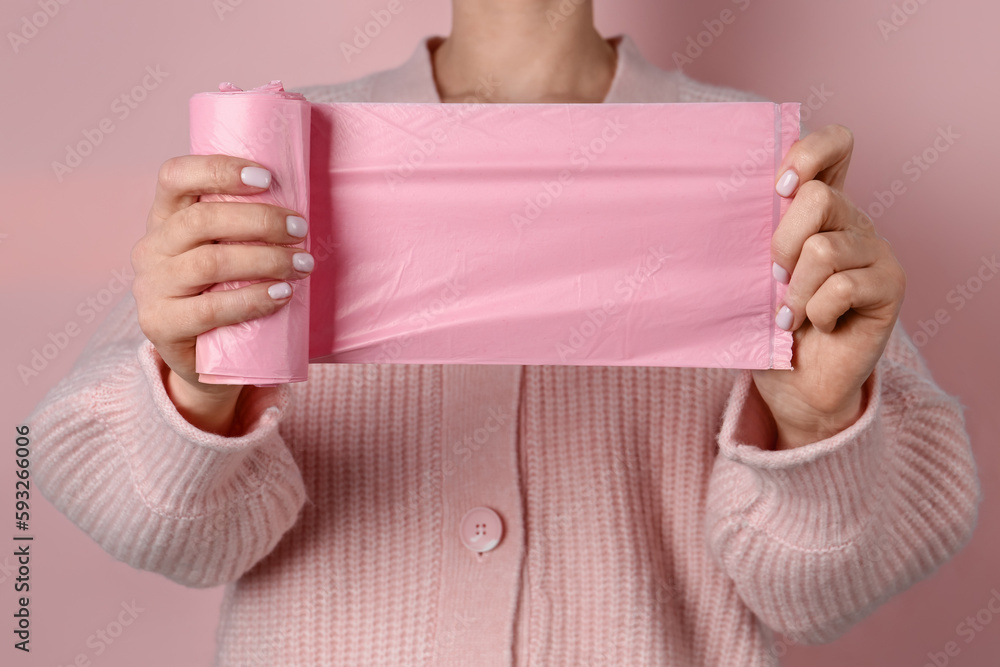 Woman holding garbage bags on pink background