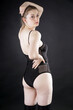 Beautiful young woman wears black body suit as lingerie or underwear in studio in front of black background