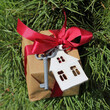 key and the layout of the house are tied to a gift with a red bow on the background of an evergreen tree. property with a garden