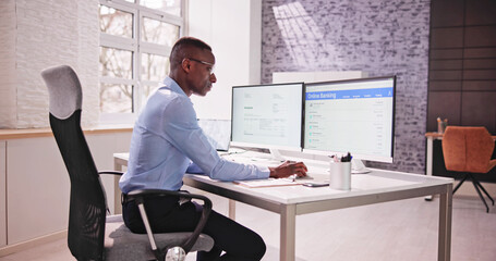 Wall Mural - Young Businessman Looking At Invoice While Doing Online Banking