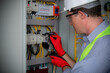 © EKKAPON - Electrician engineer work tester measuring voltage and current of power electric line in electical cabinet control.