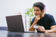 © juanpablo - Middle-aged Latin man analyzing what to buy from his laptop with his credit card.