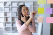 © amnaj - Asian businesswoman hand writing on sticky notes and talking on the phone. Business people meeting and writing share idea on sticky note.