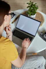 Wall Mural - Mockup white screen laptop woman using computer while sitting at table at home, back view