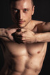© vladorlov - Adult attractive man with a beautiful body posing in the studio. Black background.