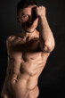 © vladorlov - Adult attractive man with a beautiful body posing in the studio. Black background.