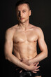 © vladorlov - Adult attractive man with a beautiful body posing in the studio. Black background.